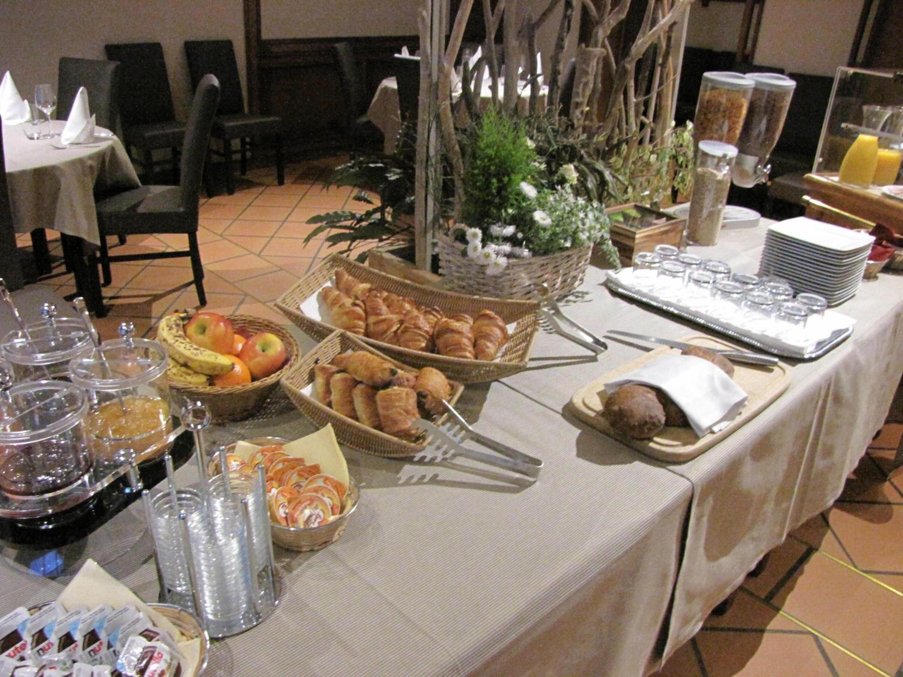 Uma mesa de buffet com diversos alimentos, incluindo frutas, doces e acompanhamentos.