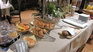 Uma mesa de buffet com diversos alimentos, incluindo frutas, doces e acompanhamentos.
