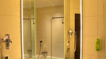 A modern bathroom with a large mirror, a round sink, and a shower area.