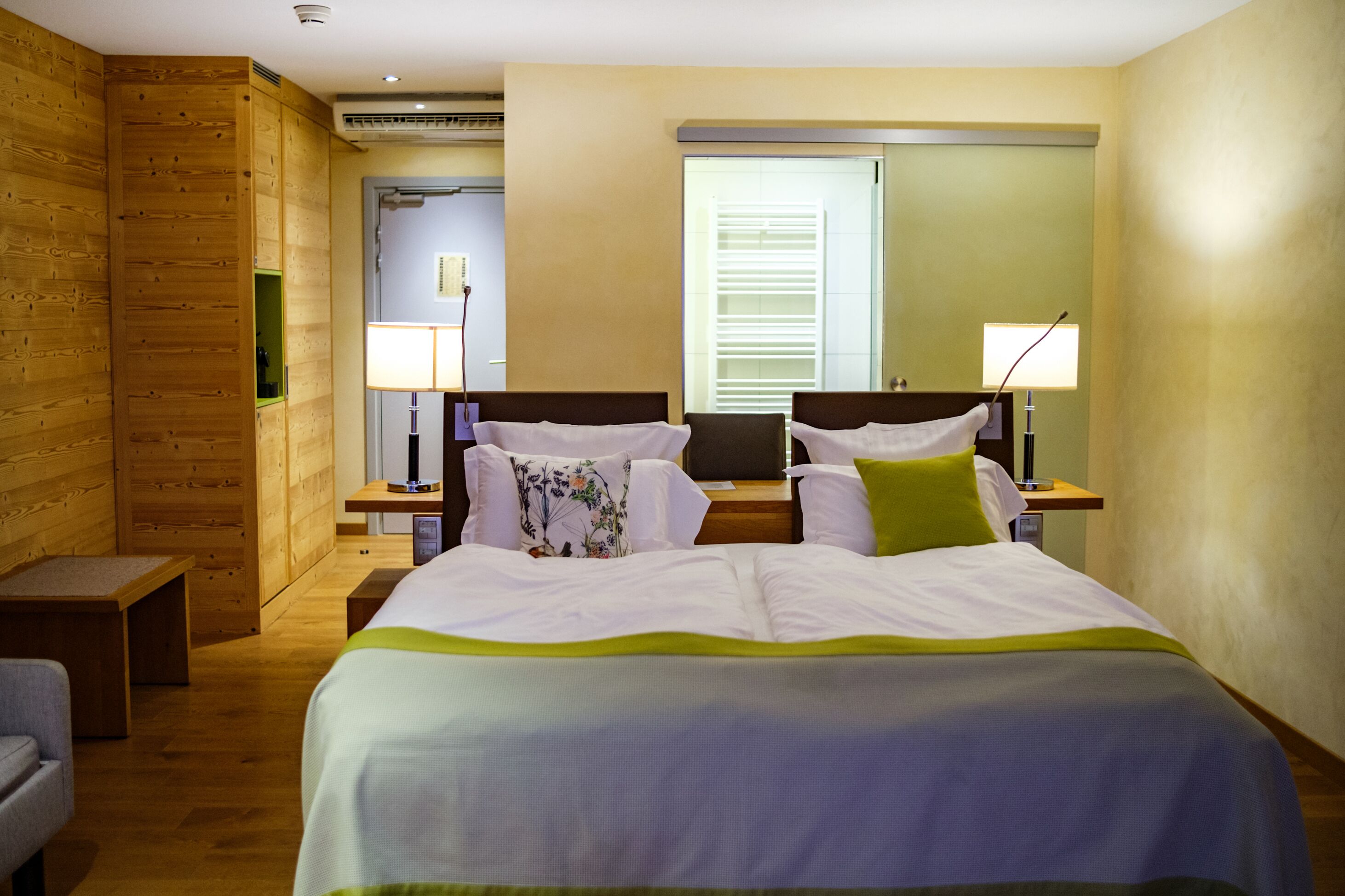 Una habitación de hotel con una cama grande, dos mesitas de noche, un escritorio y una silla.