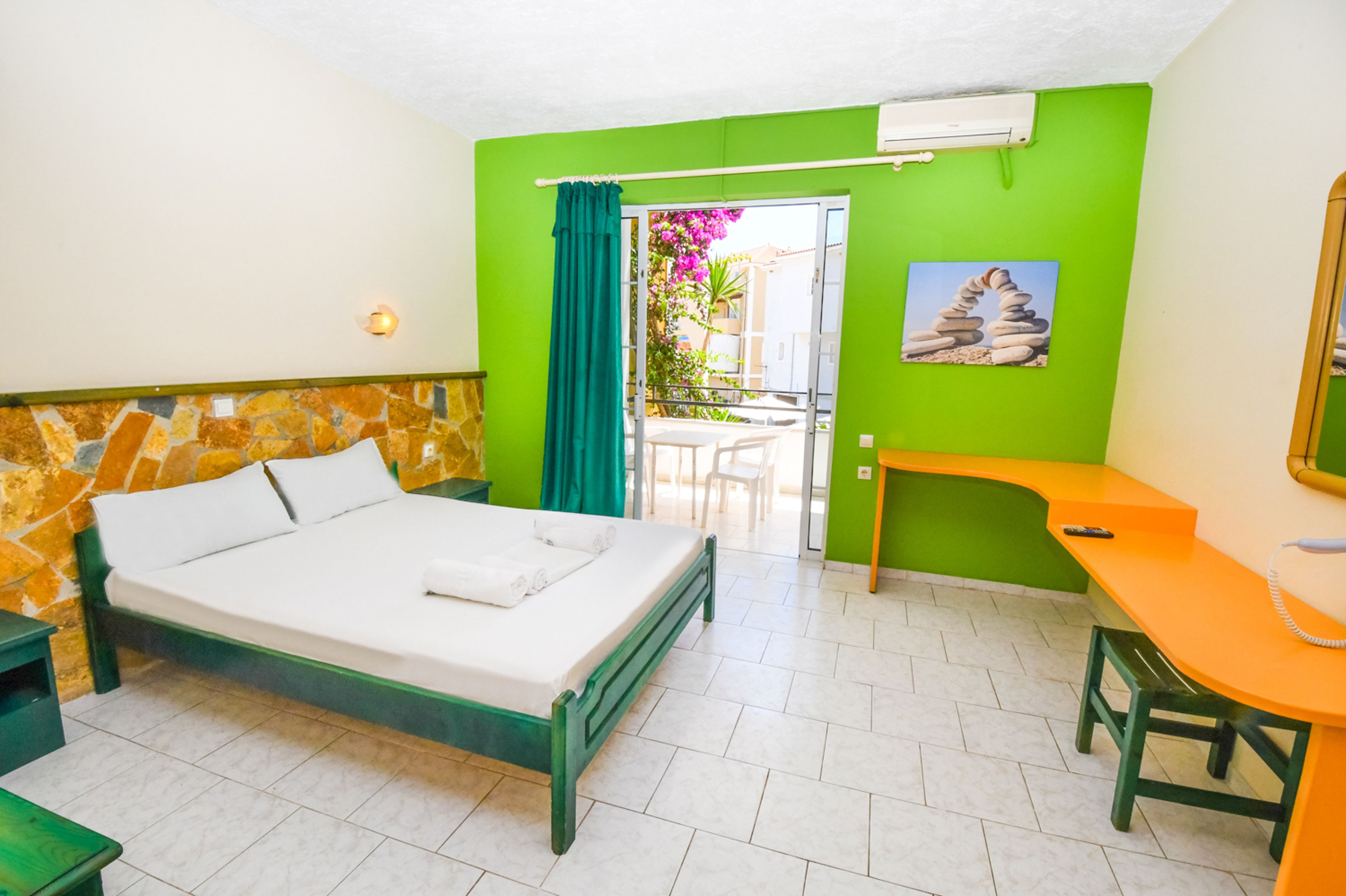 A hotel room with a bed, a desk, a chair, and a view of the outside.