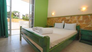 A room with a bed, a green wall, a stone accent wall, and a view through a glass door.