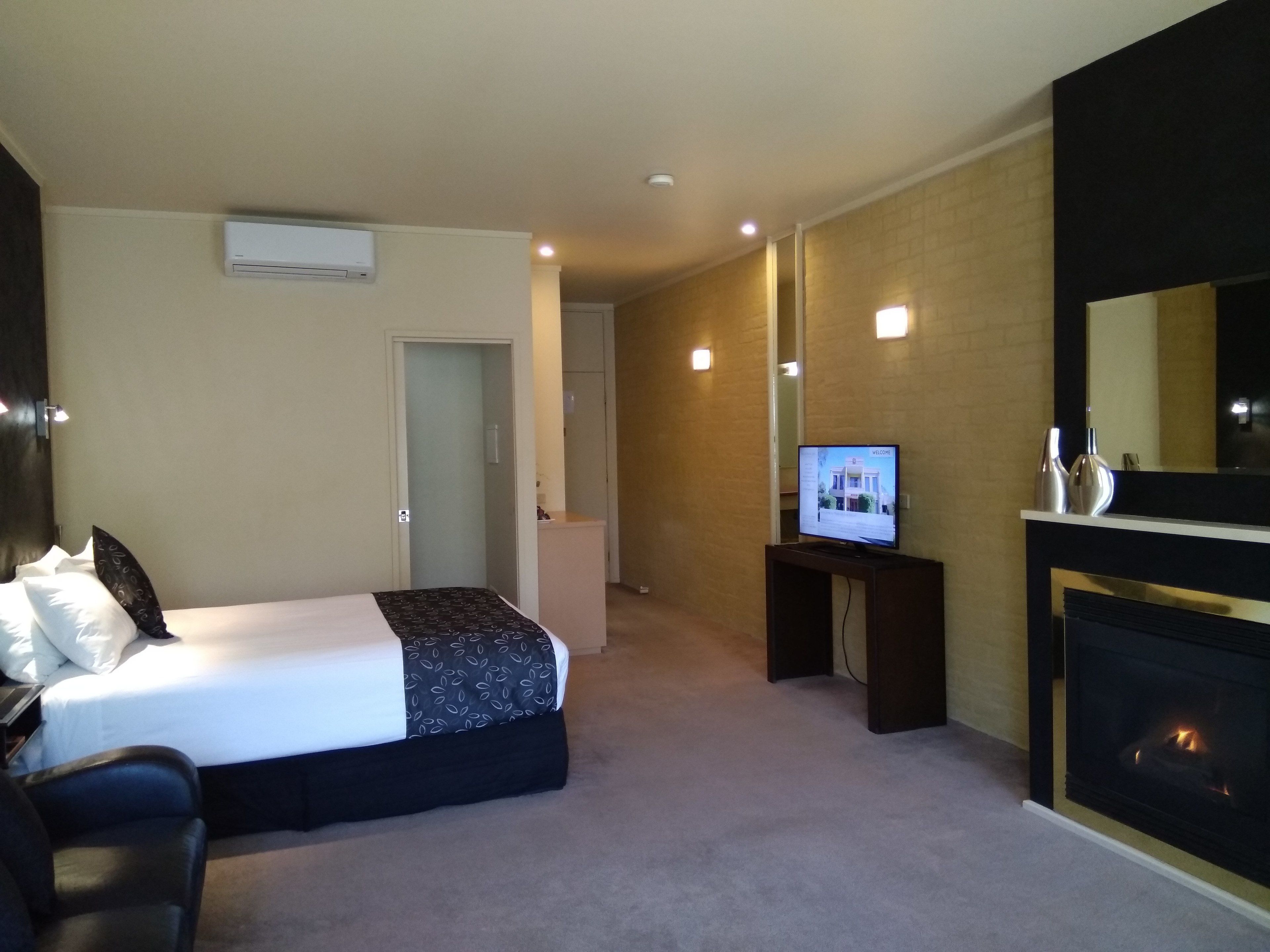 Una habitación de hotel con una cama, televisión, chimenea y una puerta que da a otra habitación.