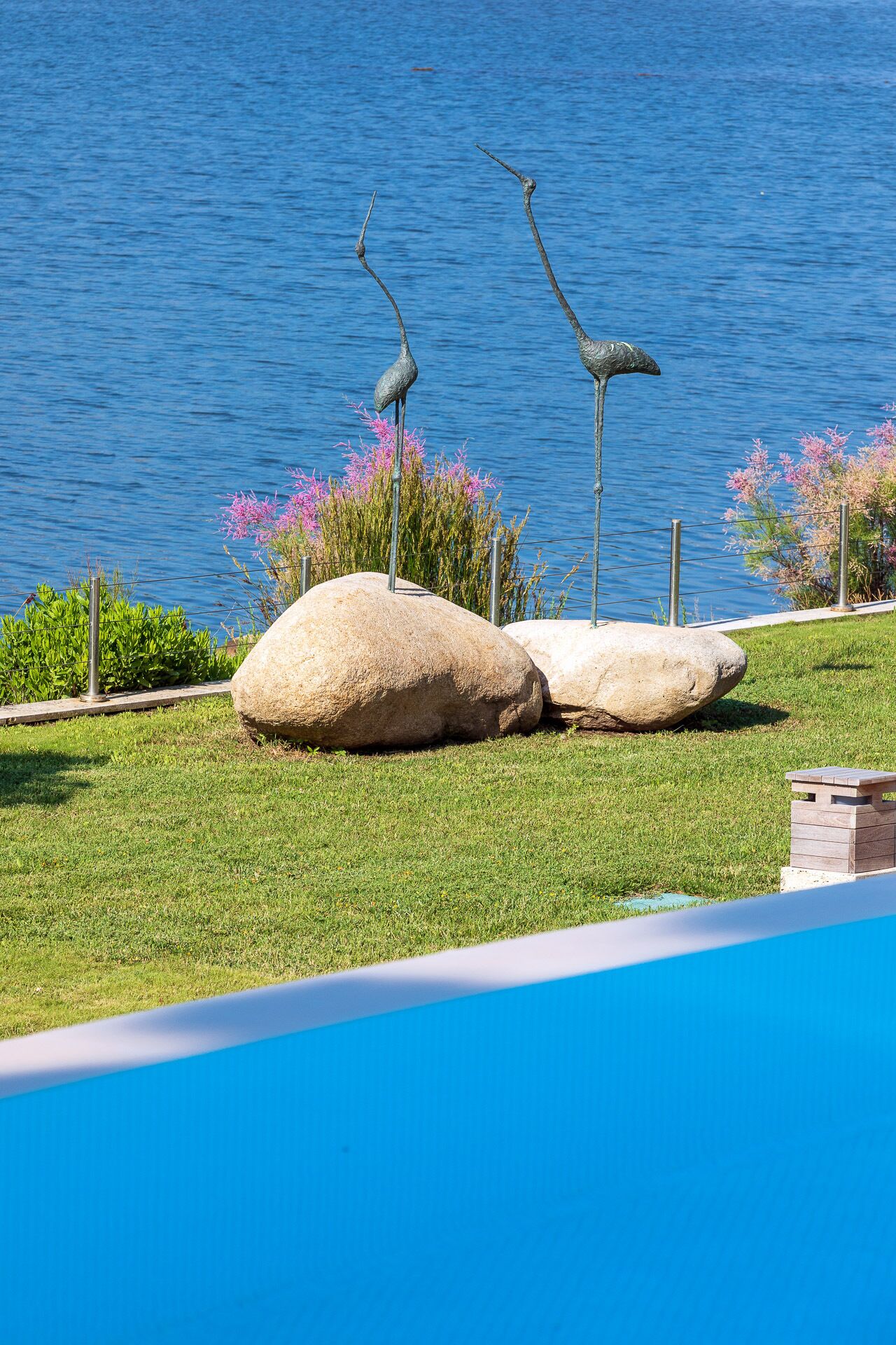 Un área de piscina con rocas grandes y esculturas de aves.