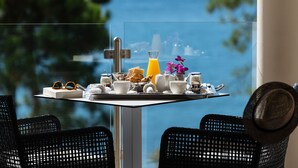 Een ontbijttafel met een glas sinaasappelsap, een vaas met paarse bloemen en diverse ontbijtartikelen.