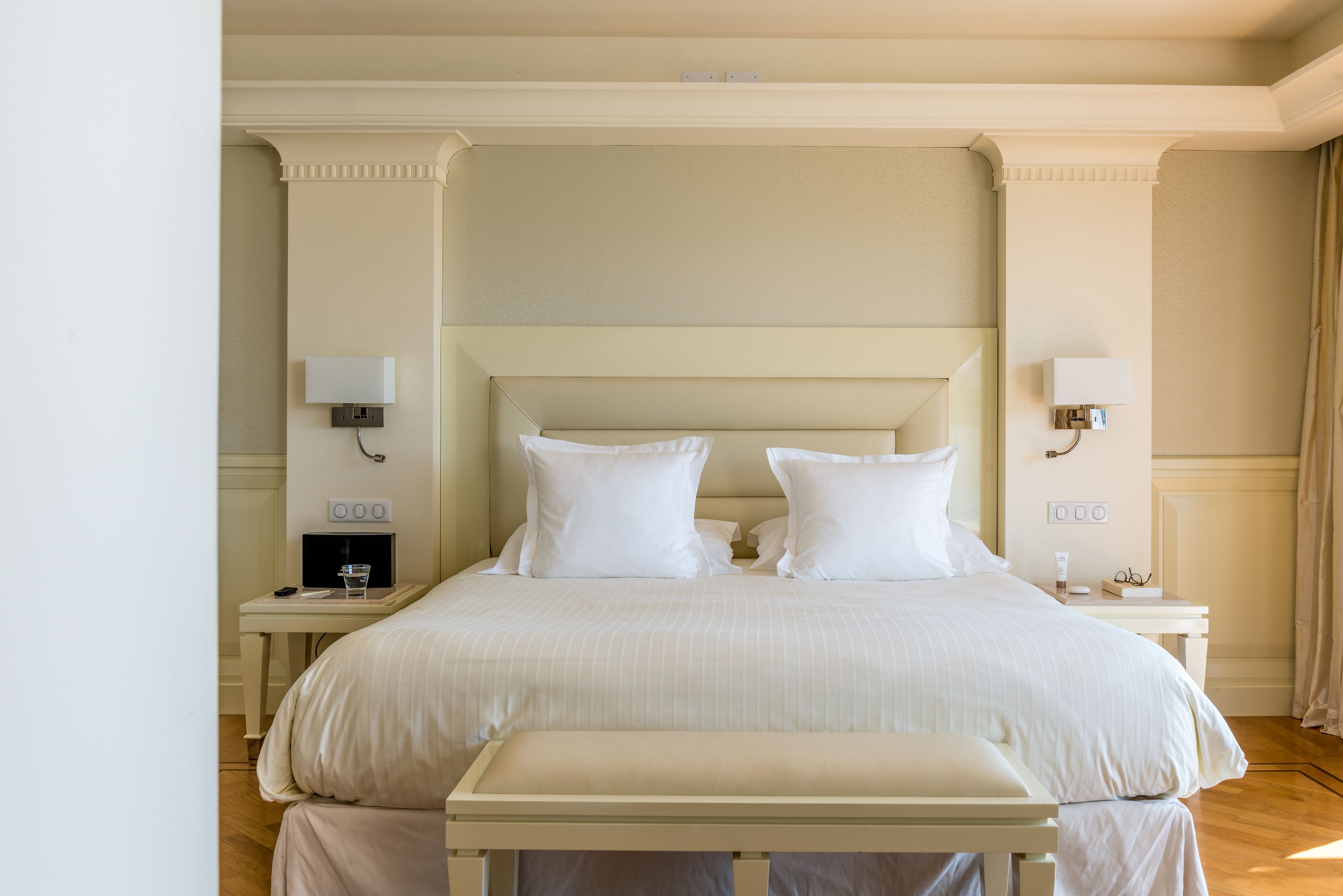 Una habitación de hotel ordenada con una cama grande, mesitas de noche y lámparas fijadas a la pared.