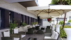 Un espace extérieur aménagé avec des meubles en osier et un pot de fleurs suspendu.