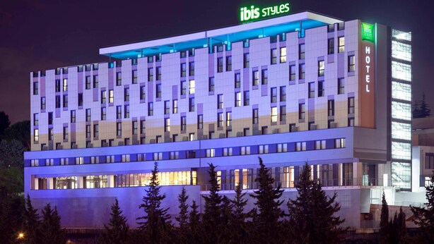 Un hôtel à plusieurs étages au design moderne, avec une enseigne « ibis styles » bien visible sur le toit.