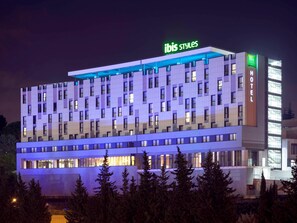 Ett hotell med flera våningar och modern design, med en tydlig skylt med texten ”ibis styles” på taket.