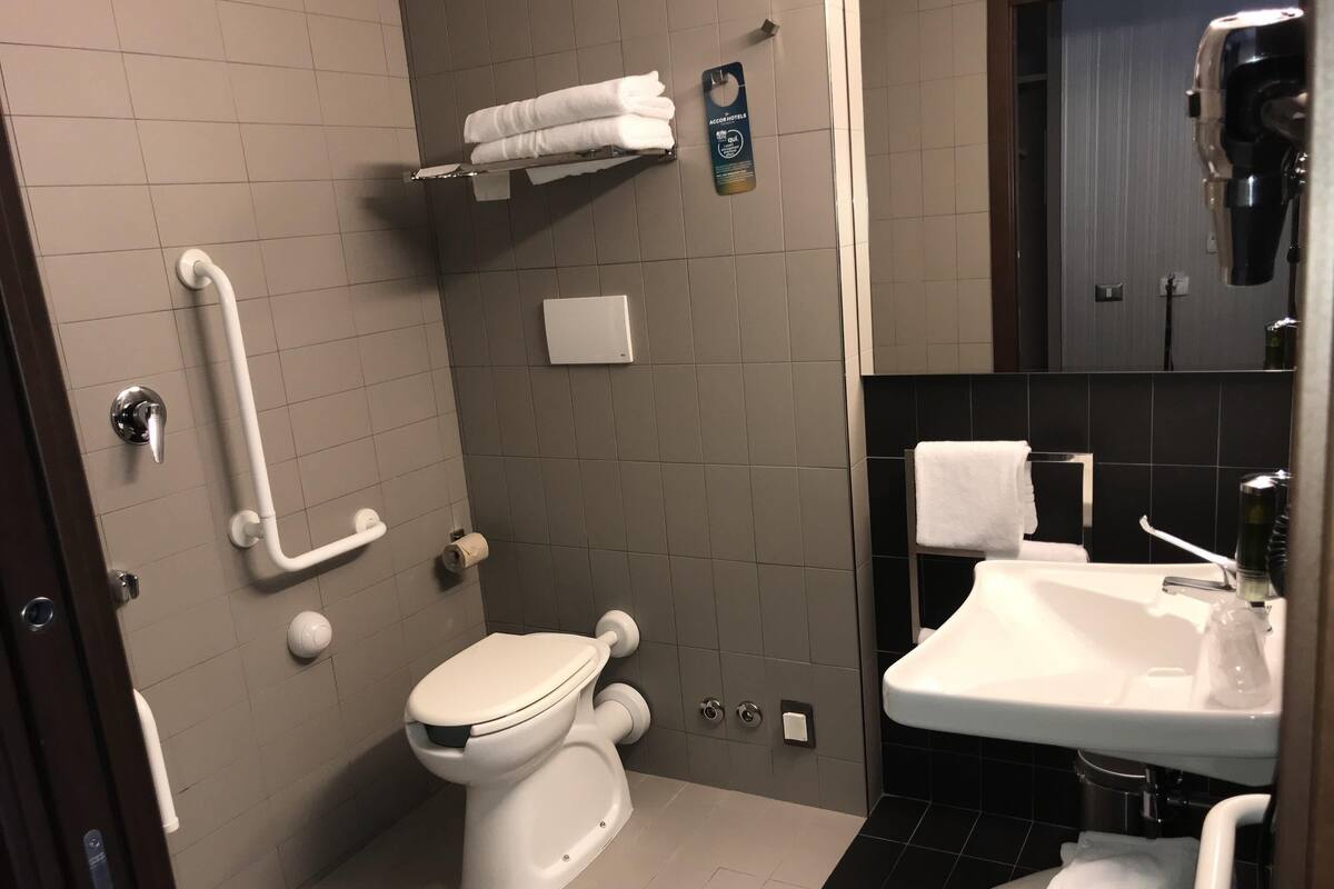 Een moderne badkamer met toilet, wastafel en handdroger.