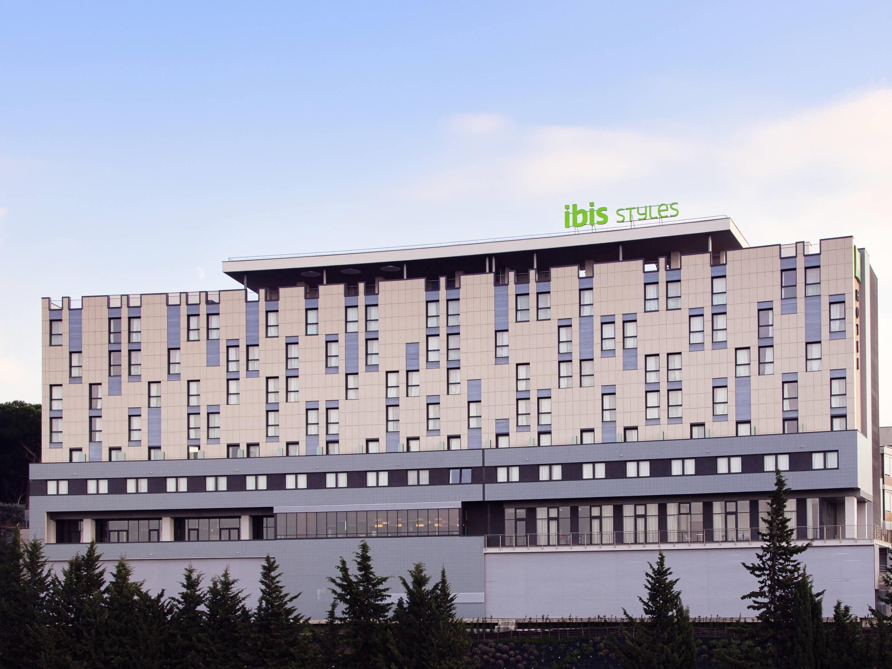 A modern hotel building with a flat roof and a sign reading "ibis styles".