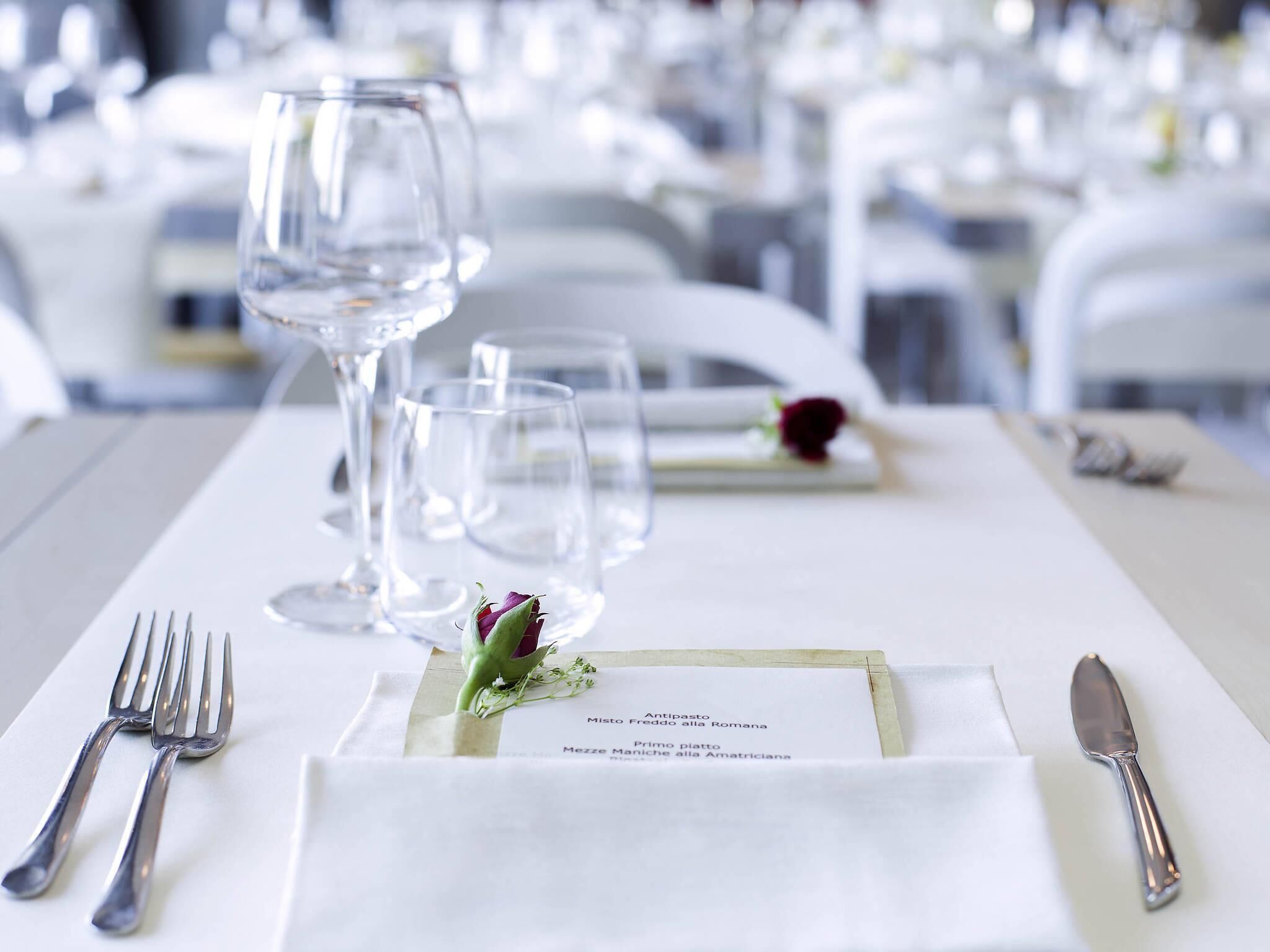 Mesa posta para refeição com menu, copos de vinho e talheres.