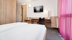 Habitación de hotel con dos camas, un escritorio, un televisor y un baño.
