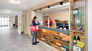 Zona de recepción con mostrador de madera, vitrina de vidrio con botellas de vino y un cartel que indica un establecimiento ecológico.