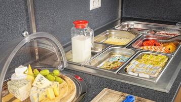 Ein Buffet mit verschiedenen Speisen, darunter Käse, Obst und verpackten Produkten.