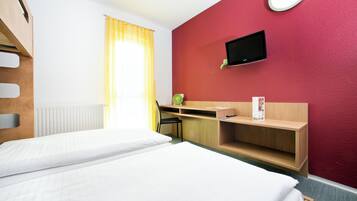 A hotel room with two beds, a desk, a chair, a TV, and a window with curtains.