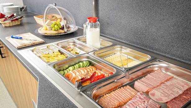 Un bufé con diversas opciones de comida, incluyendo carnes, quesos y frutas.