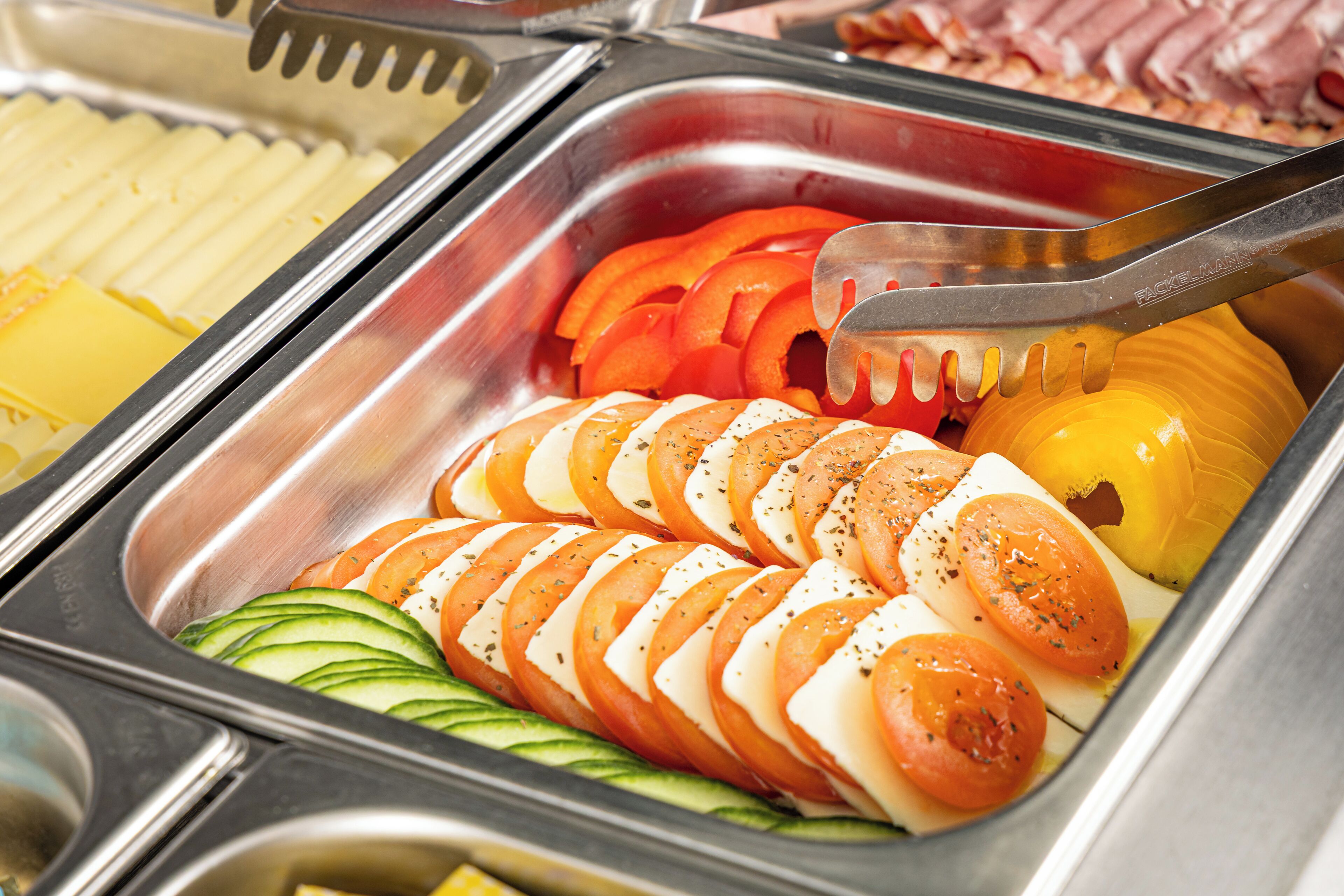 Un buffet proposant une variété d’aliments, notamment des légumes et du fromage coupés en tranches.
