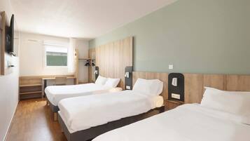 A hotel room with three single beds, a desk, and a chair.