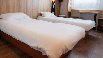 Une chambre avec deux lits simples, un bureau en bois et une chaise.