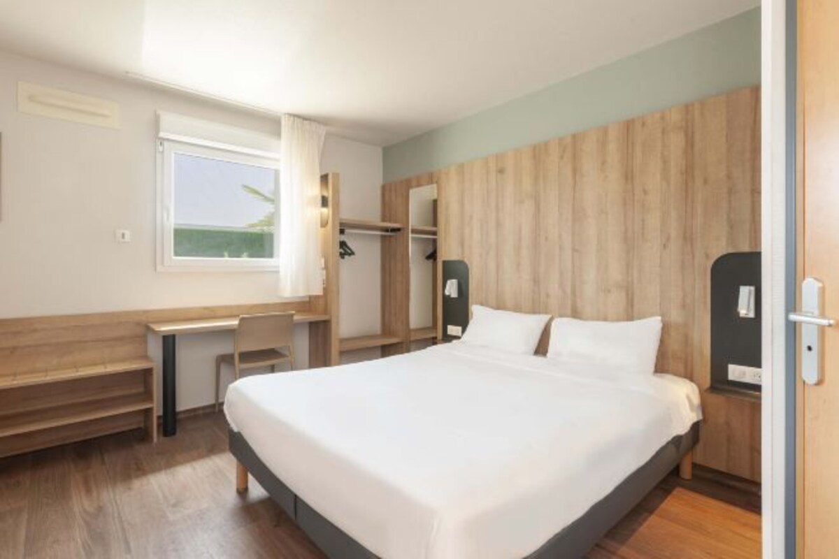 Una habitación de hotel moderna con una cama grande, un escritorio y un armario.
