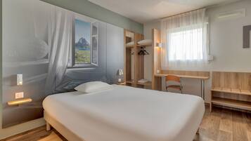 Una habitación de hotel moderna con una cama grande, un escritorio y un armario.