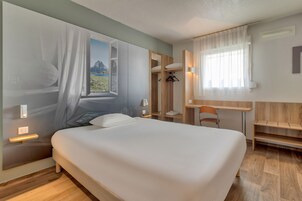 Una habitación de hotel moderna con una cama grande, un escritorio y un armario.