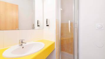 A bathroom with a yellow sink, a mirror, and a glass shower enclosure.