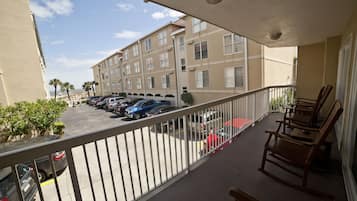 A balcony with a view of a parking lot and a building with multiple windows.