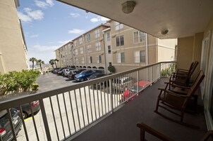 A balcony with a view of a parking lot and a building with multiple windows.