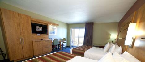 Habitación de hotel con dos camas, televisión, escritorio con silla y balcón.