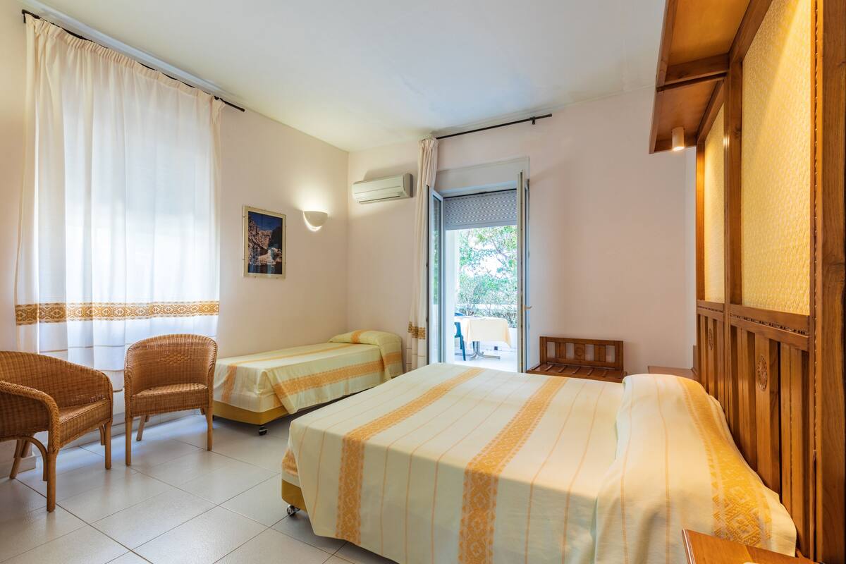 A hotel room with two beds, a sitting area with chairs, and a view of the outdoors.