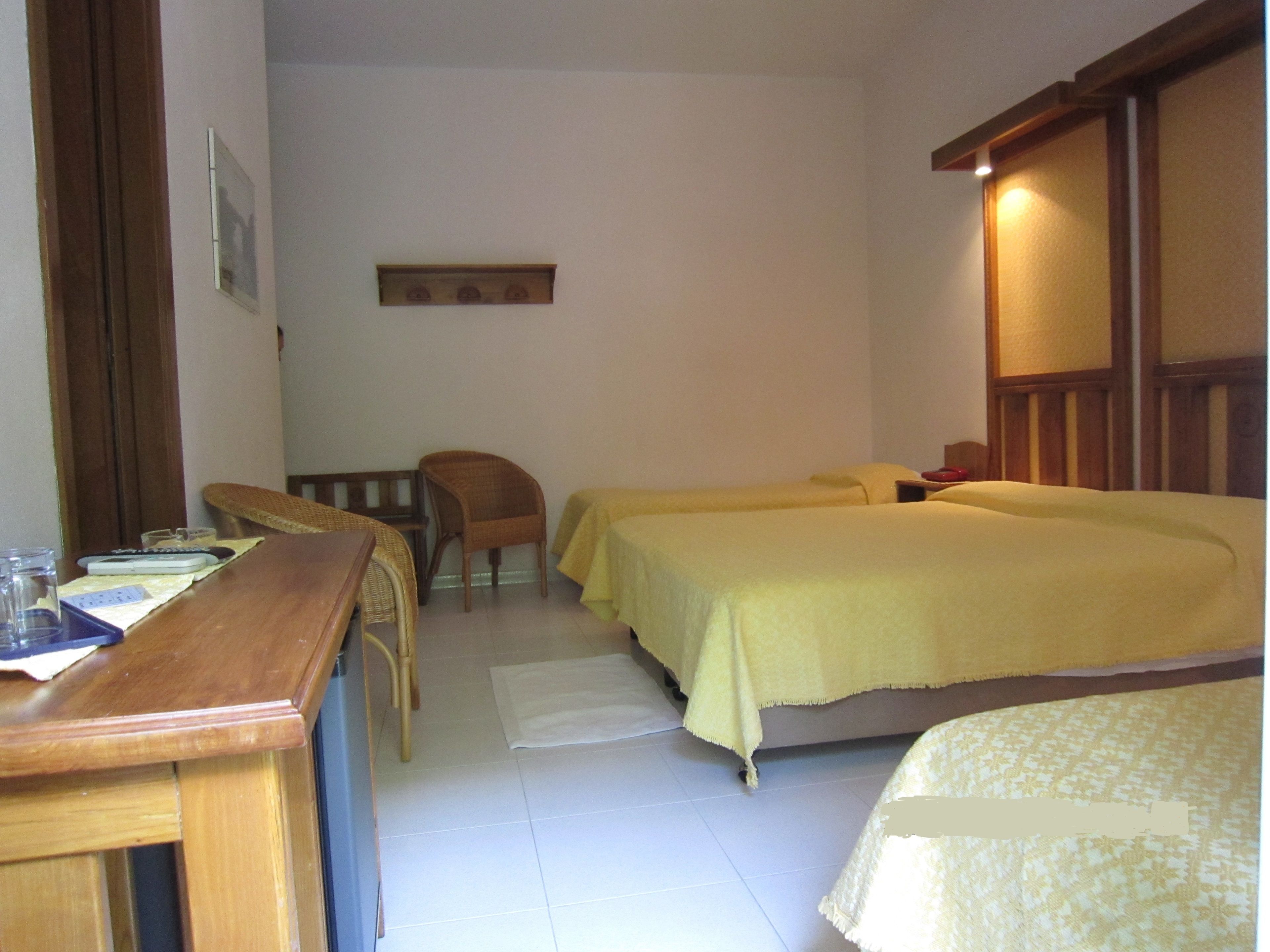 Una camera d'albergo con due letti, una scrivania in legno, una sedia e un tavolino.