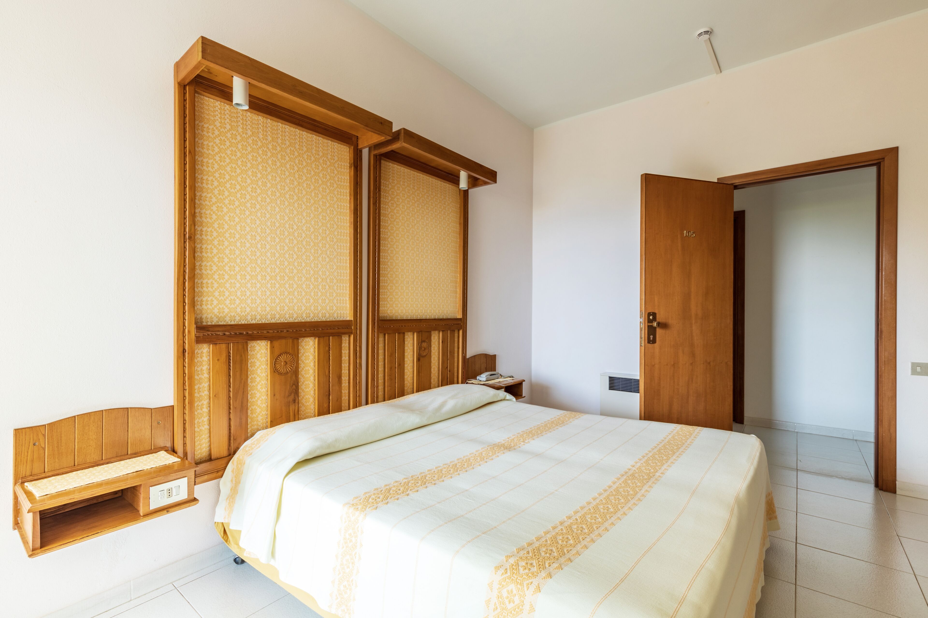 Ein Schlafzimmer mit einem Bett, einem Holzschrank, einem Nachttisch und einer Tür.