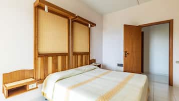 Ein Schlafzimmer mit einem Bett, einem Holzschrank, einem Nachttisch und einer Tür.