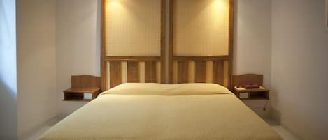 A hotel room with a large bed, wooden headboard, bedside tables, and a nightstand.