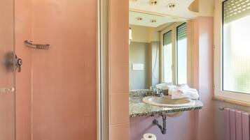 Une salle de bain avec des carreaux roses, un lavabo en granit, un miroir et une fenêtre.
