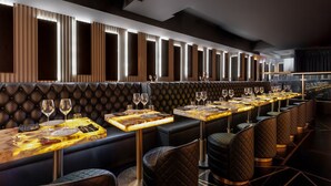 A modern restaurant with leather booths and tables, featuring a long counter and a view of the city.