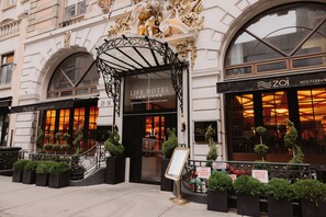 The Life Hotel New York entrance with a wrought iron canopy, a signboard, and potted plants. - Life Hotel New York (New York)
