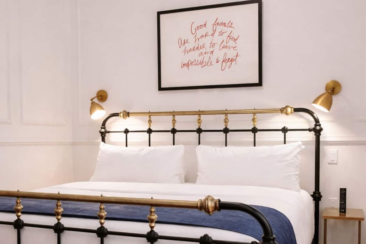 A bed with a black and white frame, a blue bed skirt, and two bedside lamps.