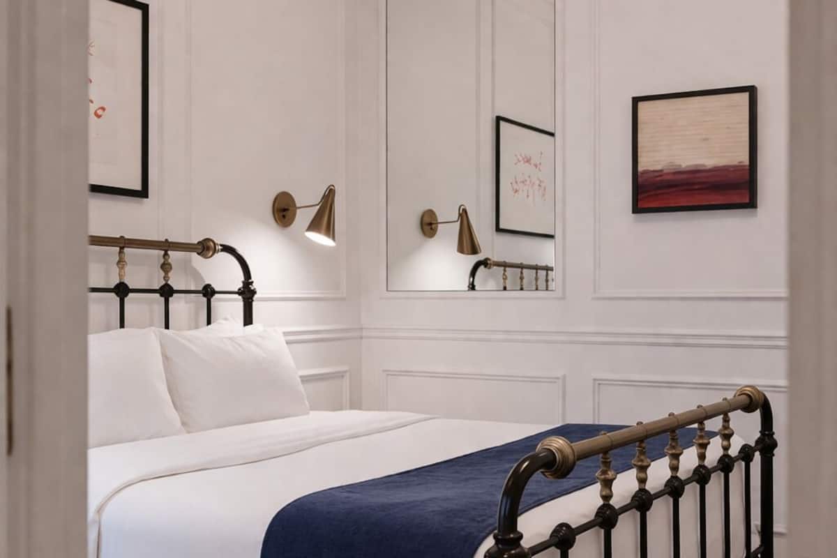 A bedroom with a bed, a large mirror, and a chandelier.