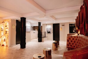 A hotel lobby with a central column, a reception desk, and a seating area with a red upholstered sofa. - Life Hotel New York (New York)