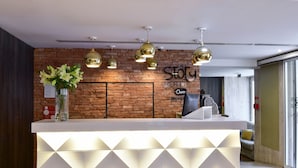 A reception desk with a white counter, a brick wall, and a sign that reads "Story Hotel." - My Story Hotel Ouro (Lisbon)