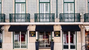 A hotel with a traditional facade, featuring ornate window frames and a balcony with decorative iron railings. - My Story Hotel Ouro (Lisbon)