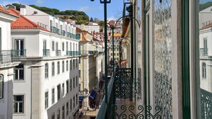 A narrow street with buildings on either side, a metal balcony railing, and a clear blue sky. - My Story Hotel Ouro (Lisbon)