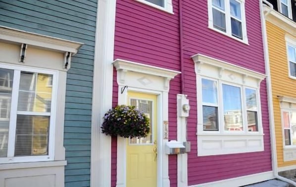 A row of colorful houses with distinct siding colors and white trim.