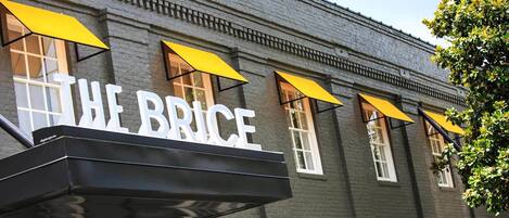 Un bâtiment portant l’enseigne « THE BRICE » et surmonté d’auvents jaunes au-dessus des fenêtres.