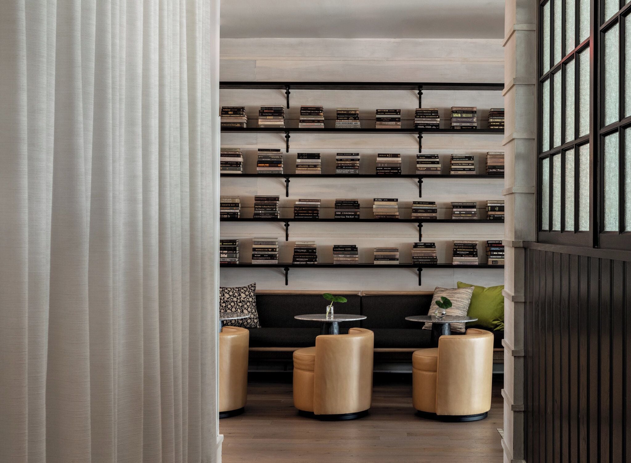 A modern reading area with leather ottomans, a small table, and a bookshelf filled with books.