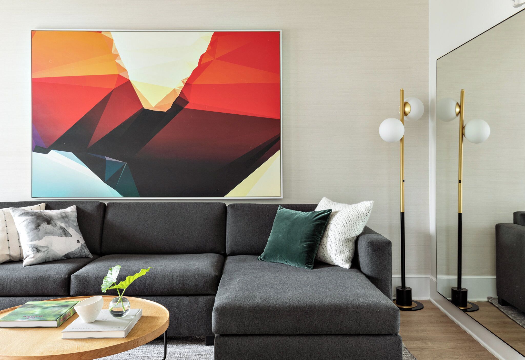 Ein modernes Wohnzimmer mit einem grauen Ecksofa, einem Couchtisch und einem großen abstrakten Gemälde an der Wand.
