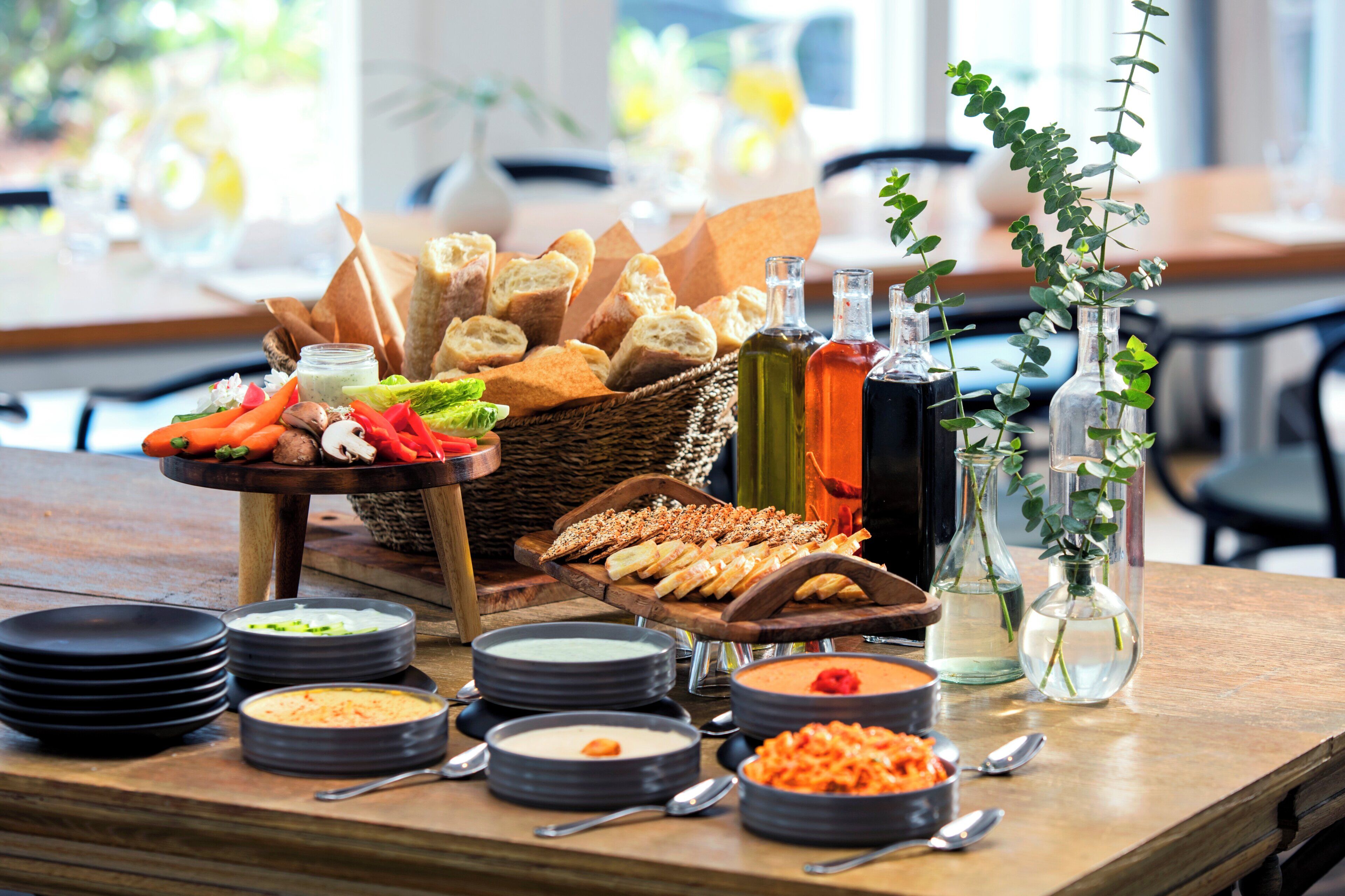 A table with various food items, including bread, dips, and sauces, arranged for a buffet.
